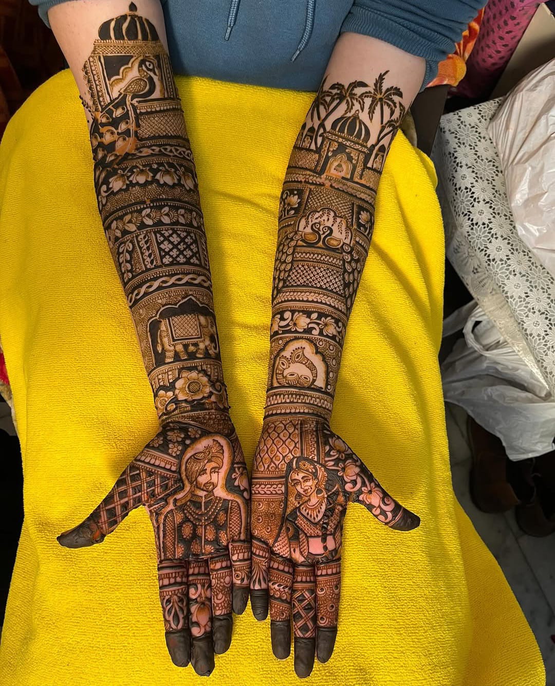 Long bridal mehndi sleeves with palm trees, temples and bride groom faces