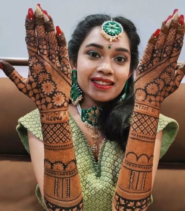 Bride showing floral mehndi with names on both arms