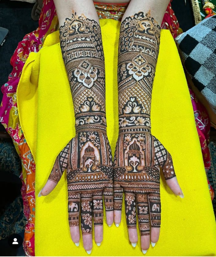Full-arm bridal mehndi with peacock crowns and temple arch palms
